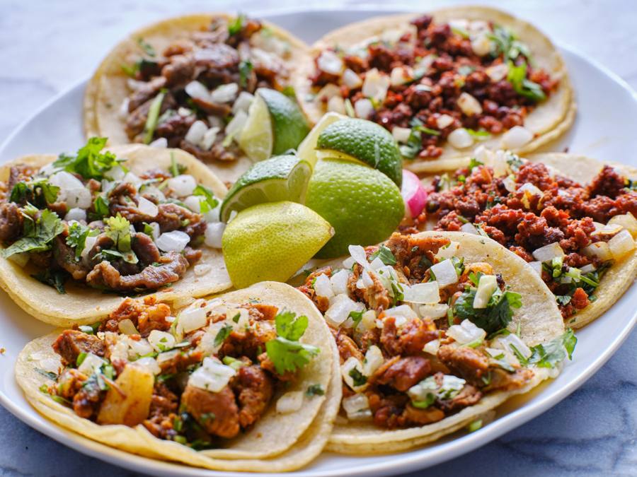 Plate of assorted street tacos with lime